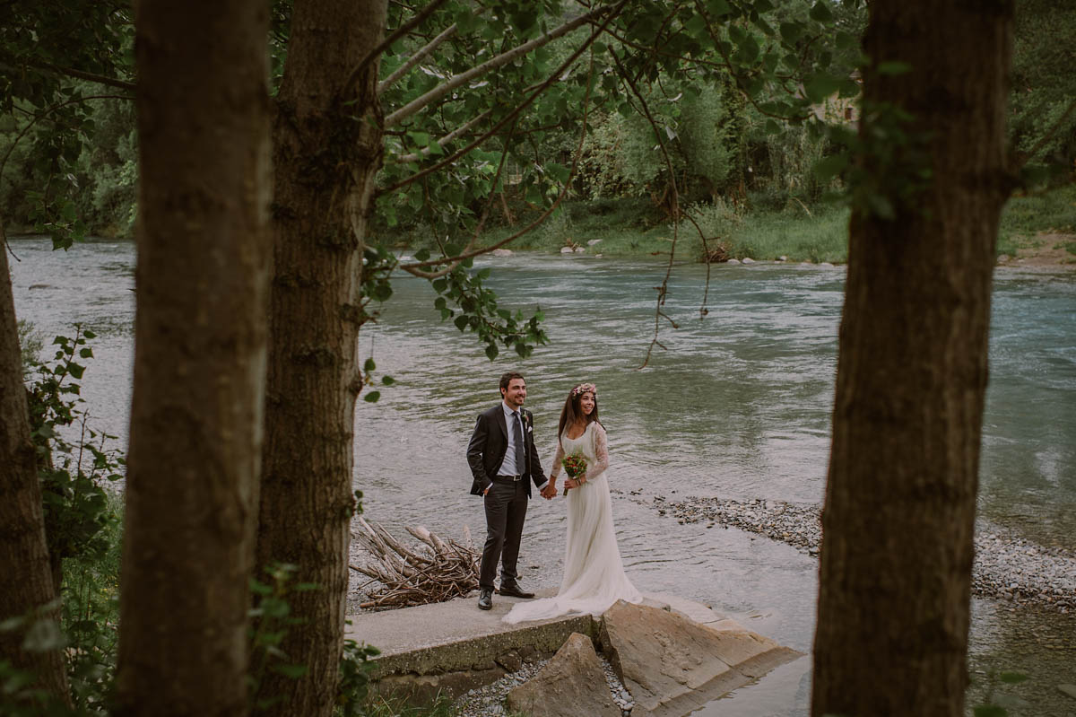 Fotógrafo en Donostia - San Sebastian, Gipuzkoa. Pareja de recién casados posan junto al río en medio de un verde bosque.